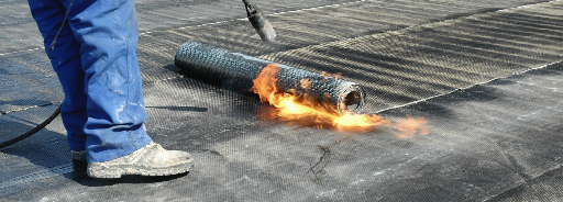Torch-on waterproofing membrane being heat-fused onto a roof surface